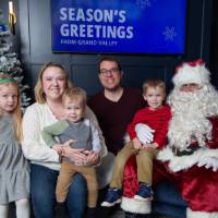 Parents with three kids smile with Santa